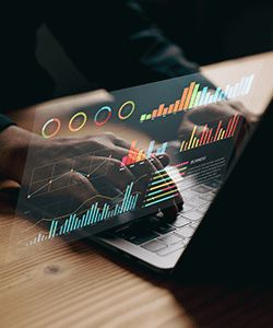 Hands on computer superimposed with graphs.