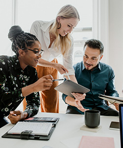 Group of three ethnically diverse people talking over a paper.