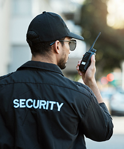 Security guard talking into a hand radio.